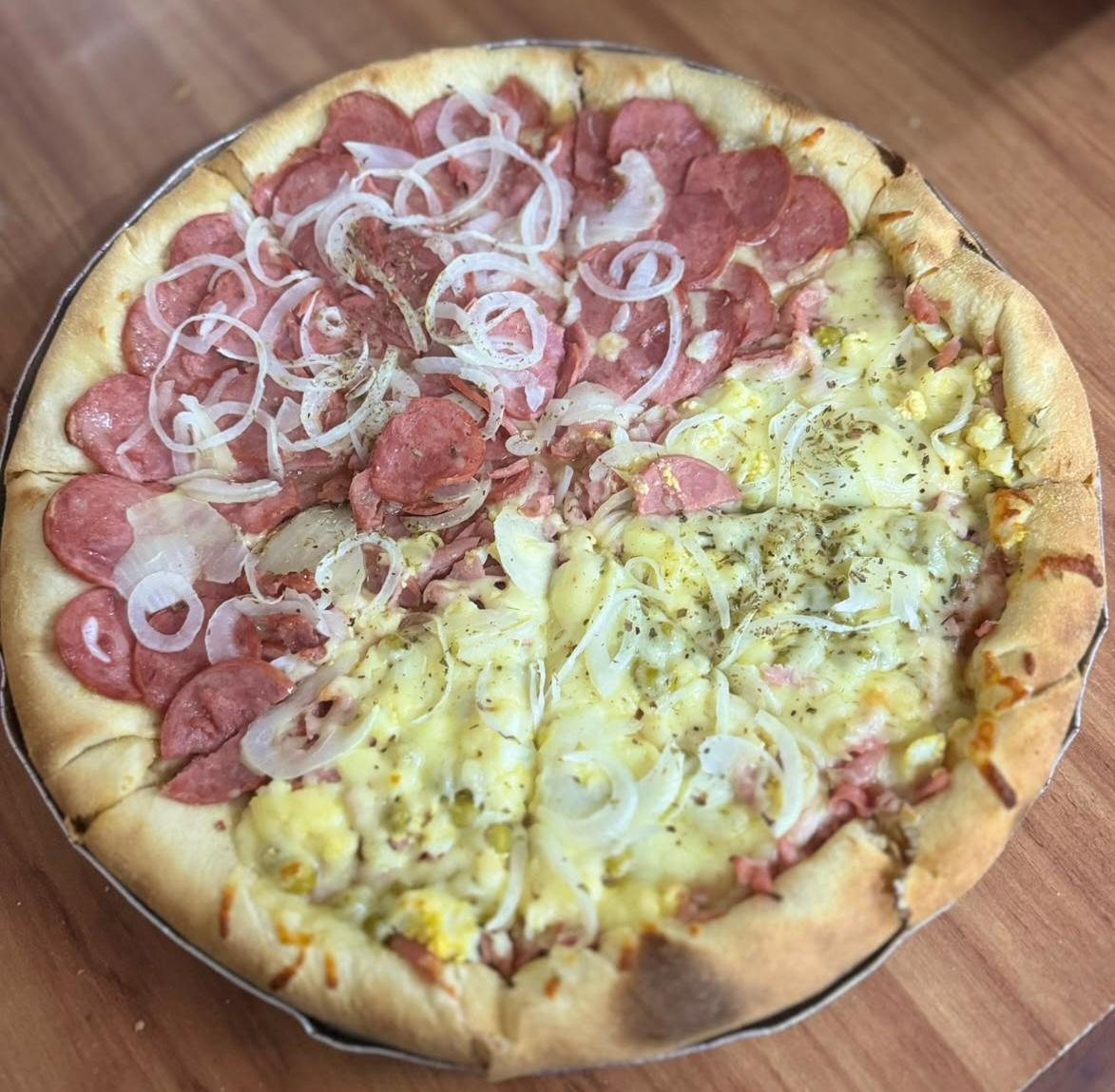 Detalhe de pizza meio a meio, close nos ingredientes de calabresa, presunto e cebola